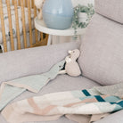 Gray sofa with a plush toy and baby blanket in a nursery setting