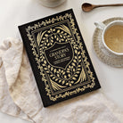 Decorative journal titled 'Grandma's Story' on a table with a cup of coffee and a spoon.