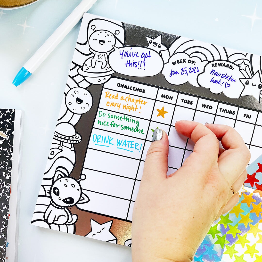 Hand holding a planner with a reward chart and stickers on a light blue background