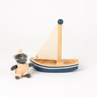 Stuffed cat next to a small wooden sailboat on a white background
