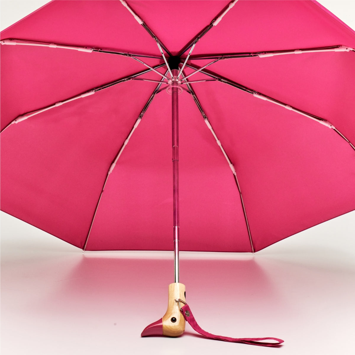 Pink umbrella with wooden handle on a pink background