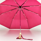 Pink umbrella with wooden handle on a pink background