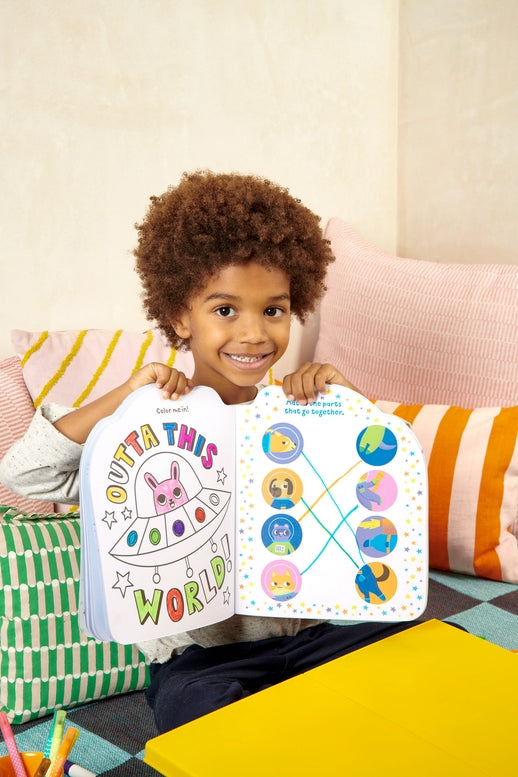 Child holding a colorful book with illustrations on a couch