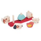 Wooden Pet Stacker toy by Mentari featuring a red base with pegs, with a black and white puppy face piece in the foreground, a blue and yellow bird piece, and a disassembled pastel blue block nearby against a plain white background.
