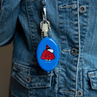 Blue retractable key holder with cartoon design attached to a denim jacket.