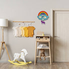 Children's room with baby clothes on a rack, rocking horse, and wooden shelf.