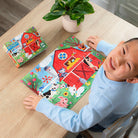 Child playing with a colorful farm-themed book on a wooden table.