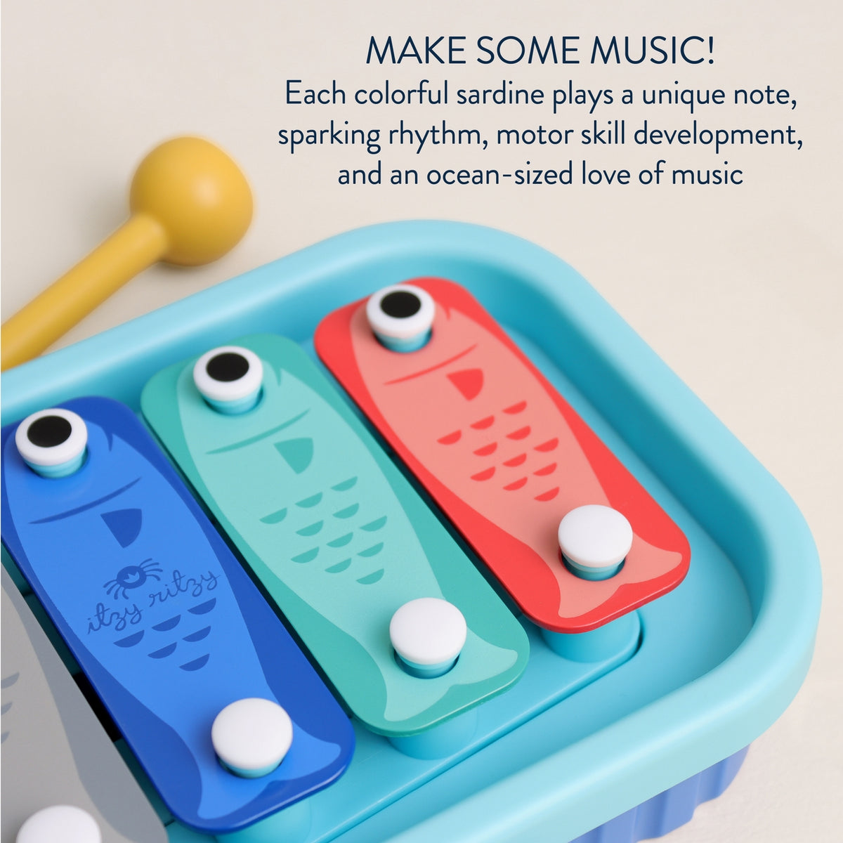 Colorful toy sardine xylophone with a maraca on a light background