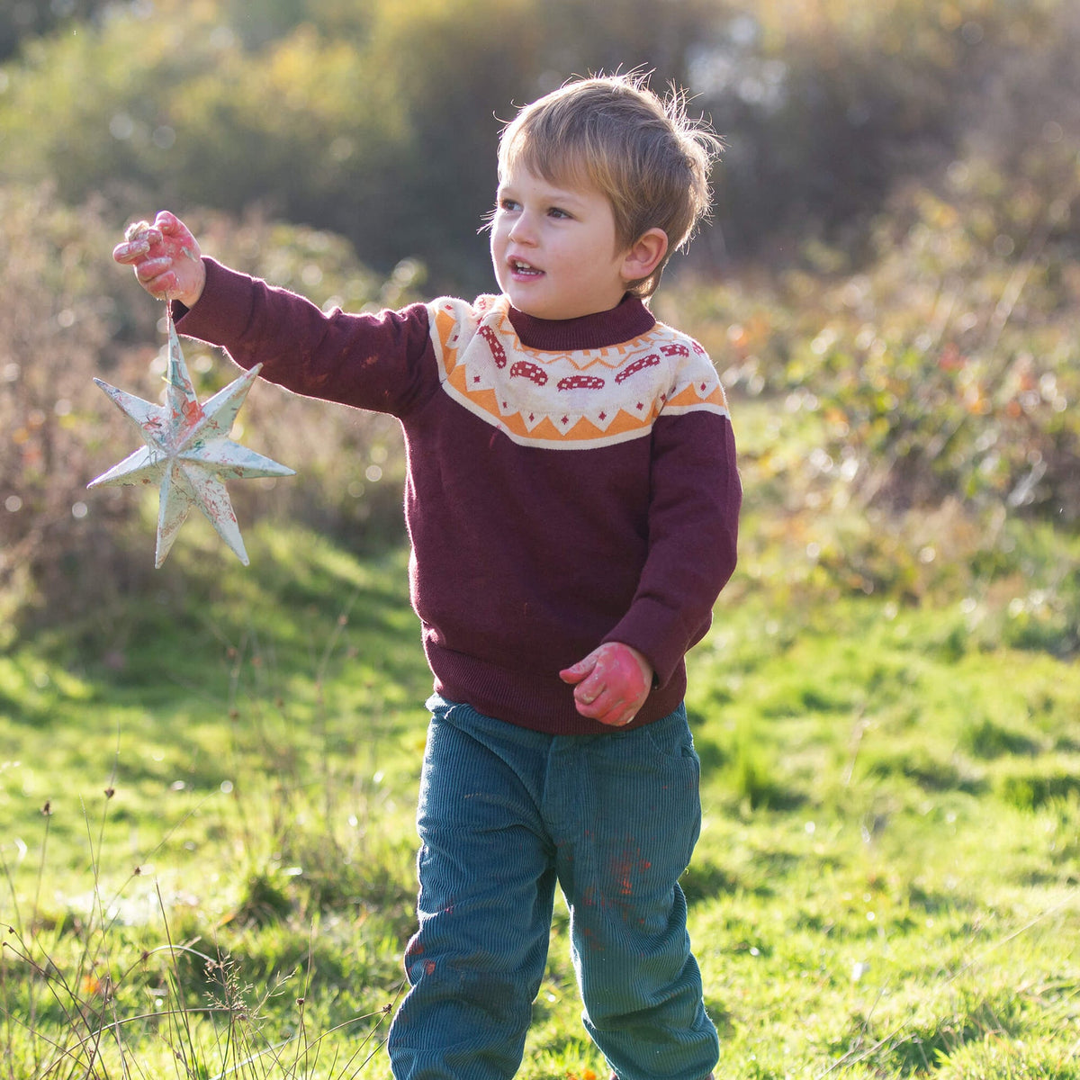 Child holding a star-shaped object in a grassy field