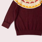 Maroon sweater with a colorful patterned collar on a light gray background