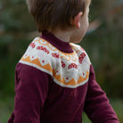 Child wearing a patterned sweater with a blurred natural background