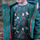 Child wearing a green jacket with a colorful patterned shirt underneath, standing outdoors.