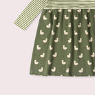 A long-sleeve baby dress in sage green, featuring a striped bodice and sleeves with a white duck print skirt, shown against a pale pink background.