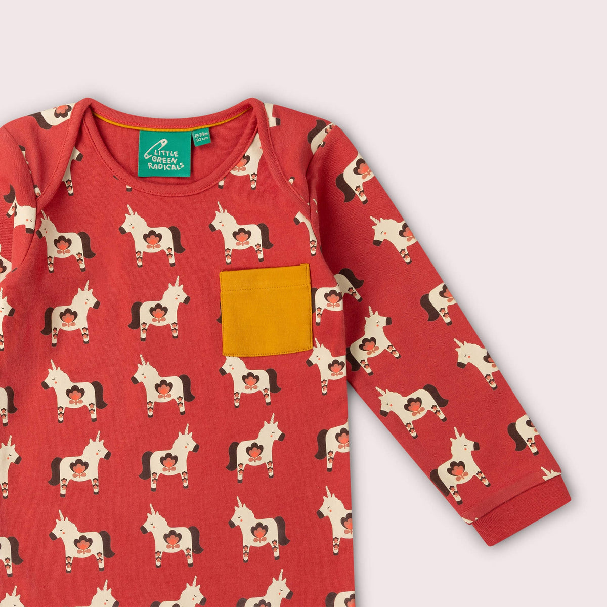 A red long-sleeve top with a repeating horse print and a mustard yellow chest pocket.