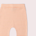 Close-up of a pair of leggings with horizontal peach and off-white stripes, showing the leg opening cutout against a pale pink background.