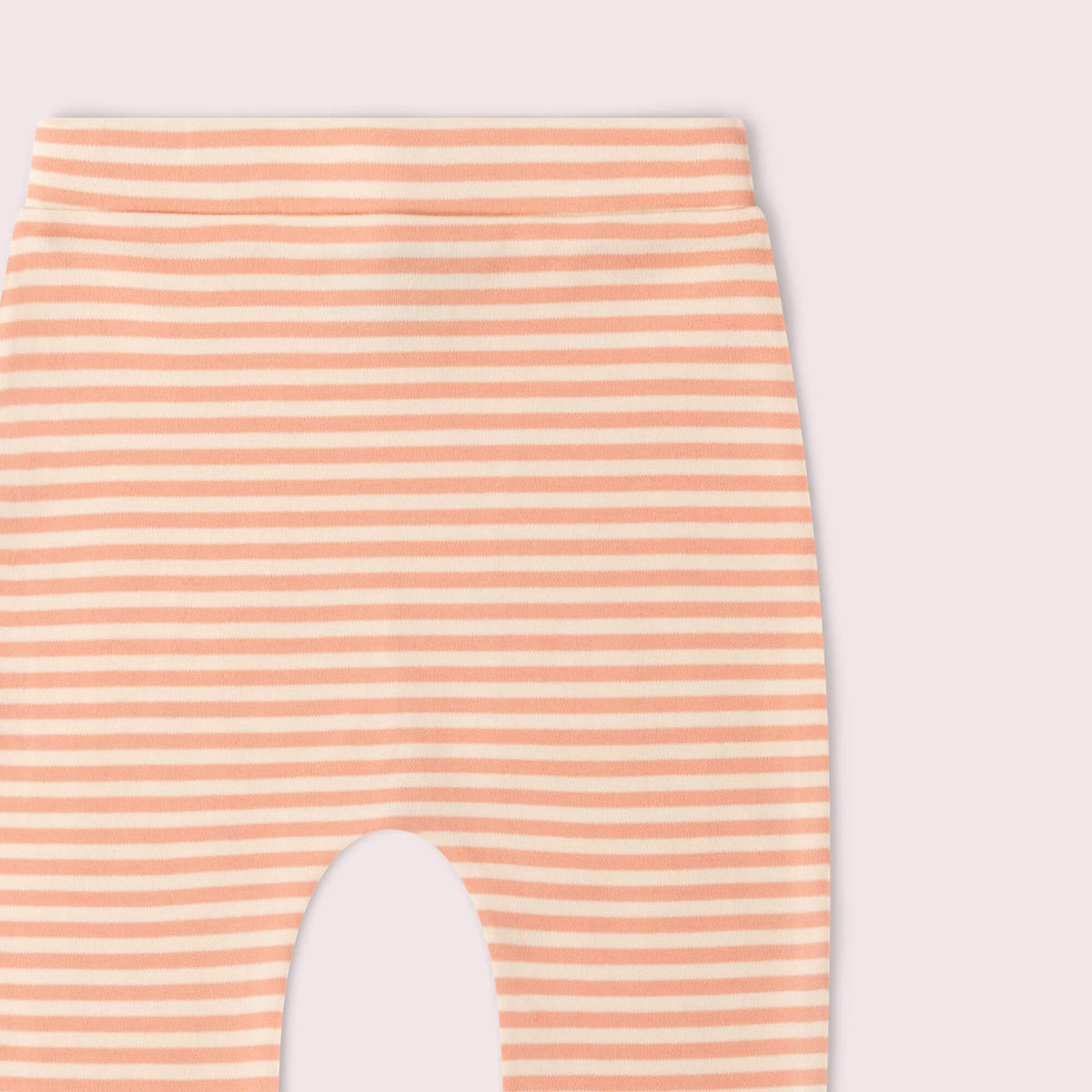 Close-up of a pair of leggings with horizontal peach and off-white stripes, showing the leg opening cutout against a pale pink background.