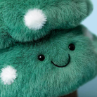 Close-up of a green plush toy with white spots and black eyes.
