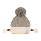A gray cable-knit beanie hat with a fluffy gray pom-pom on top, a cream ribbed lower section, and small cream pom-poms at the ends of brown ear-like extensions. A side tag reads JELLYCAT.