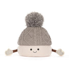A cute, smiling knit pom-pom hat with a gray cable-knit top section, a cream-colored bottom section, and small brown arms ending in cream mittens, shown on a solid white background.
