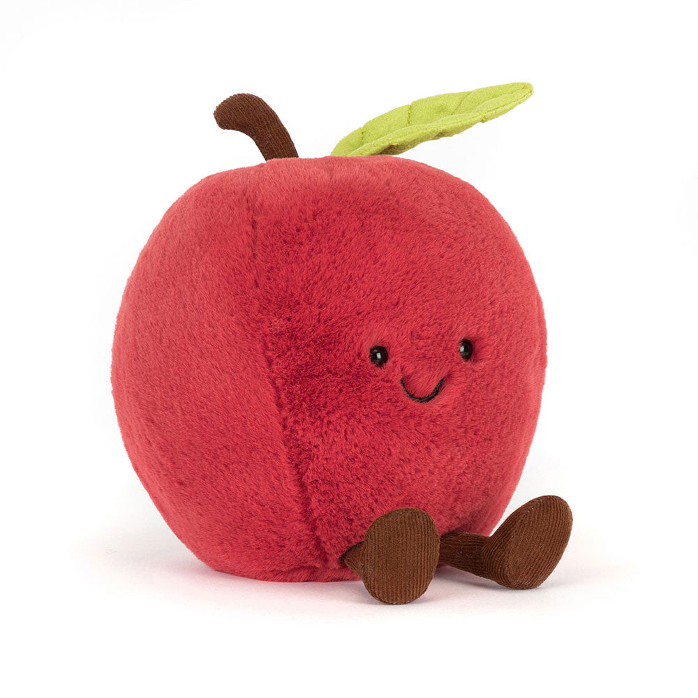 A red plush apple toy with a smiling face, a green leaf on top, and small brown corduroy legs, photographed on a clean white background.