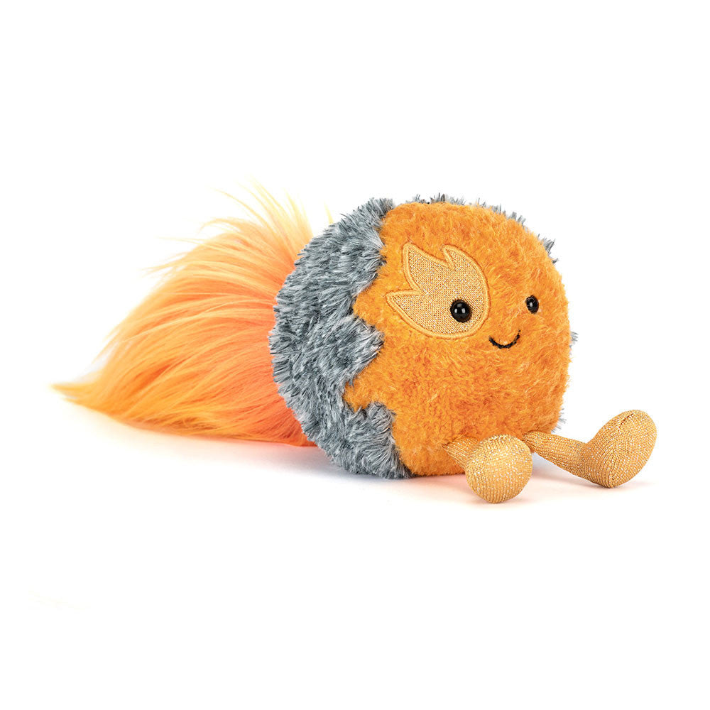A plush toy shaped like a round orange fireball with a fluffy orange tail, gray shaggy side, embroidered smiling face, and small sparkly legs, photographed on a clean white background.