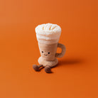 Plush toy resembling a cup of hot chocolate with whipped cream on an orange background