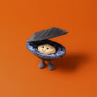Toy figure of a clam with a smiling shell on an orange background