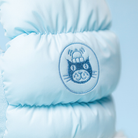 Light blue plush toy with a cat logo on a light blue background