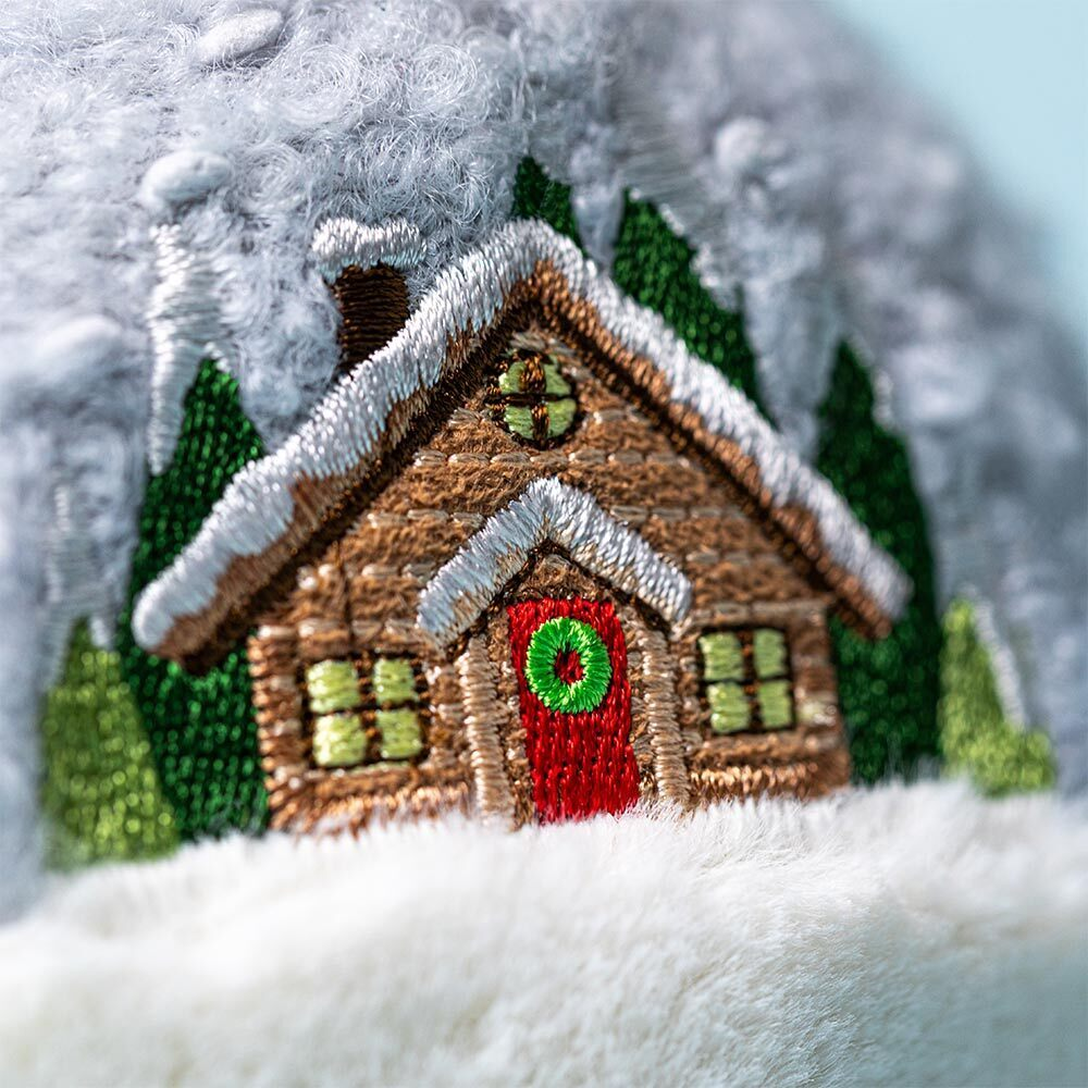 Embroidered wooden cabin with a red door and green windows on a snowy background