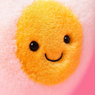 Yellow plush toy with a smiley face on a pink background