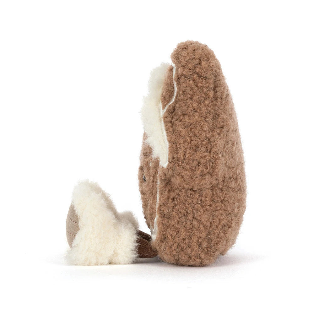 A brown textured plush toy shaped like a fox or animal character, shown from the side on a clean white background. The toy features a fluffy cream-colored inner lining and a small matching cream tail.
