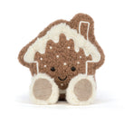 A plush toy shaped like a gingerbread house with cream-colored icing and feet, photographed on a clean white background.