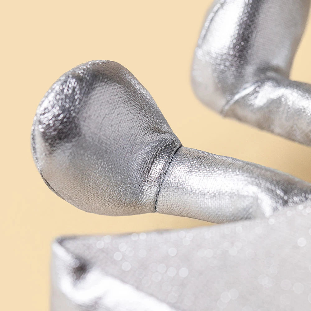 Close-up of a metallic silver textured object with a rounded end and cylindrical stem, shown against a warm beige background.