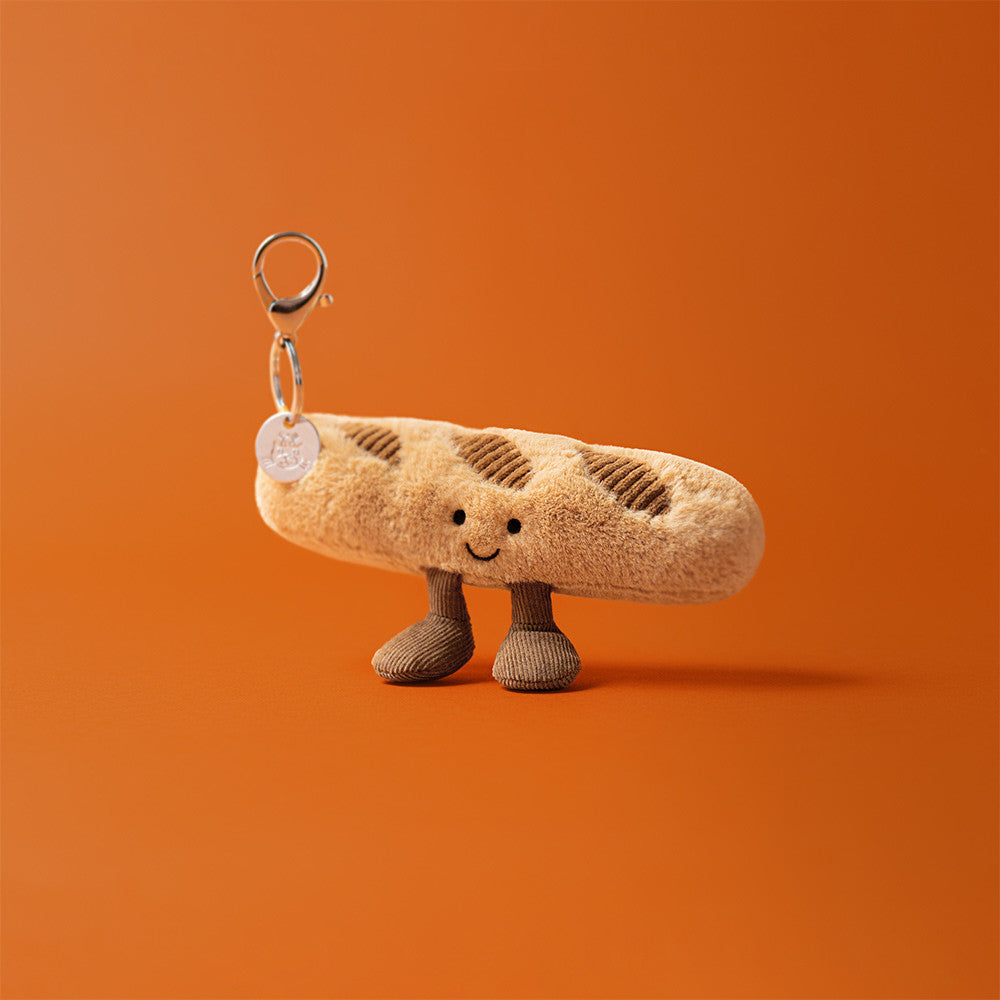 Plush baguette charm with a smiley face on an orange background