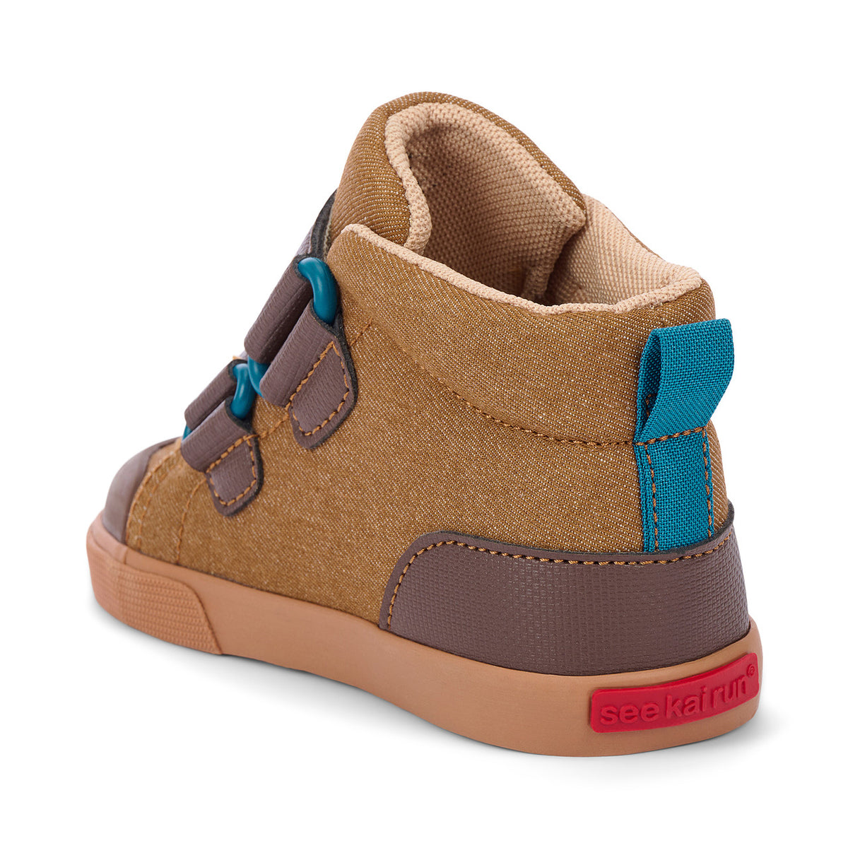A toddler's mid-top sneaker shown from the rear three-quarter view. The shoe features a tan canvas upper with brown synthetic overlays, a tan rubber sole, and bright teal accents on the laces and heel pull tab.