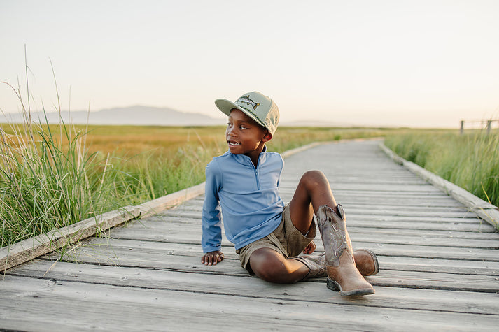 Child sitting on a wooden boardwalk in a natural setting