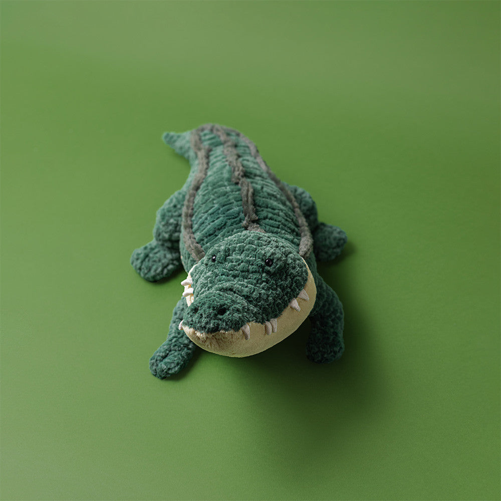 Plush toy alligator on a green background