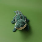 Plush toy alligator on a green background
