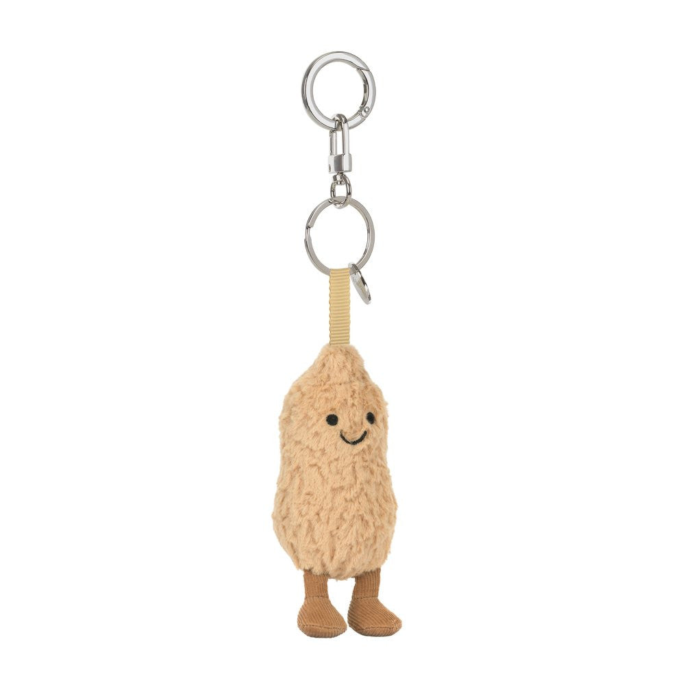 A  plush peanut-shaped keychain with a smiling face, textured beige body, brown feet.