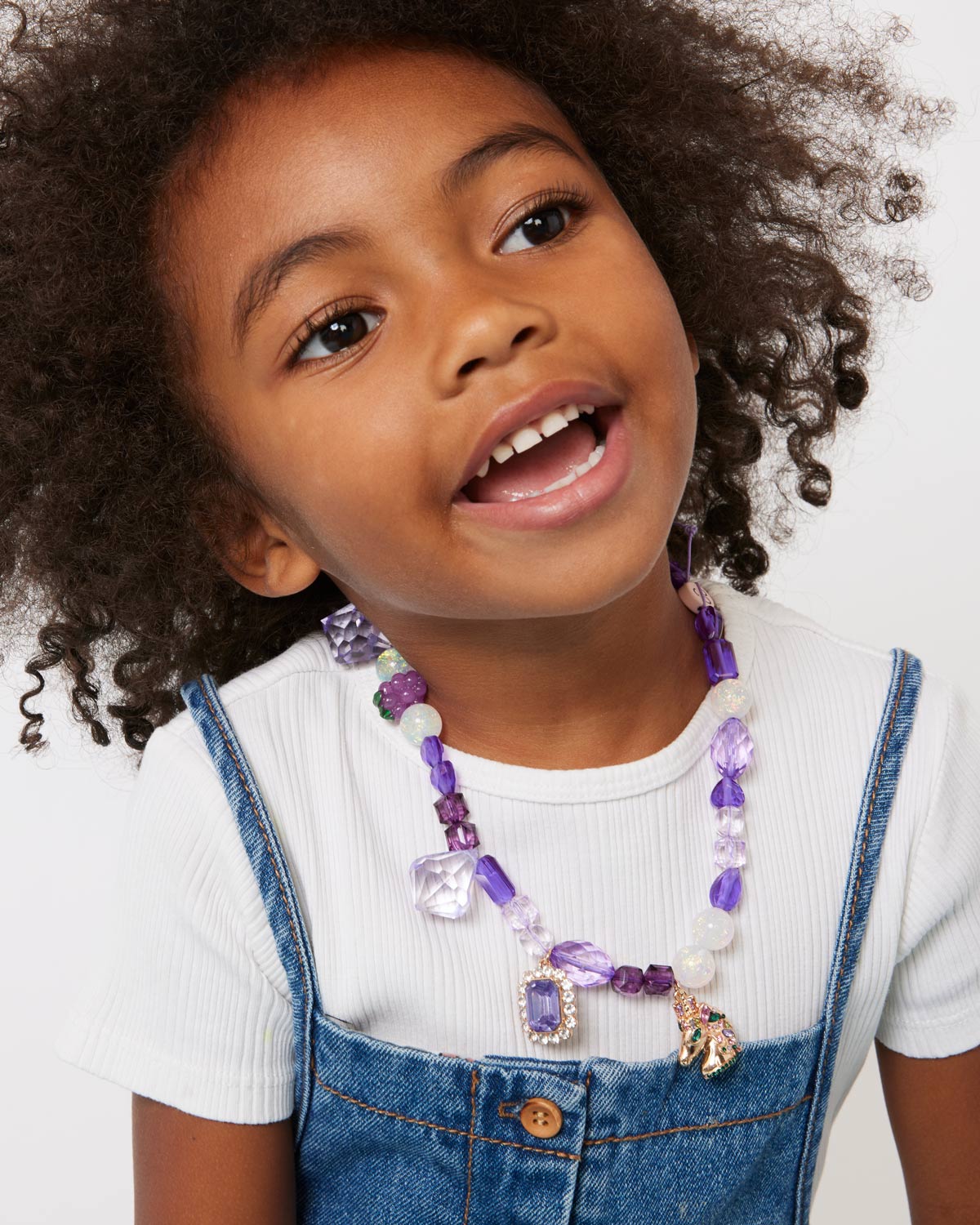 Child wearing a colorful necklace with a white background