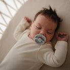 Newborn baby sleeping with a pacifier in a crib