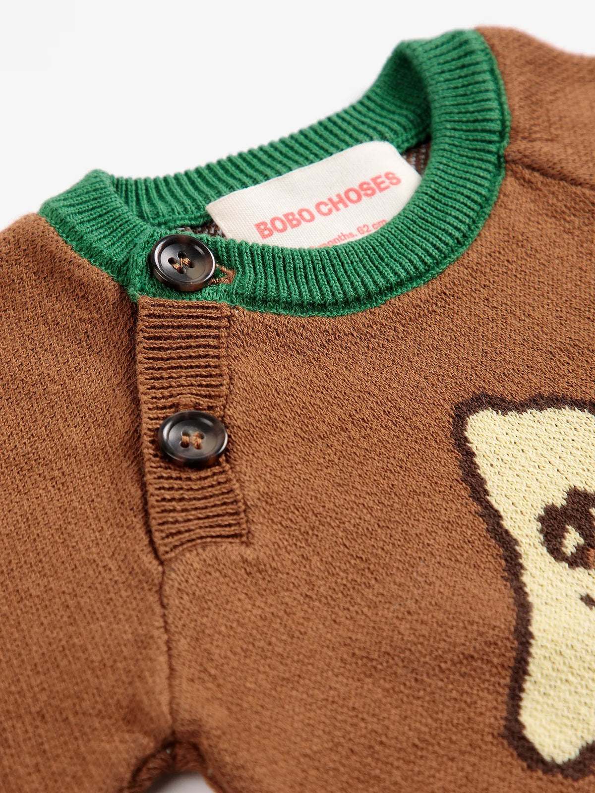 Close-up of a brown knit sweater with a green ribbed collar, two dark buttons, and a visible BOBO CHOSES neck label.
