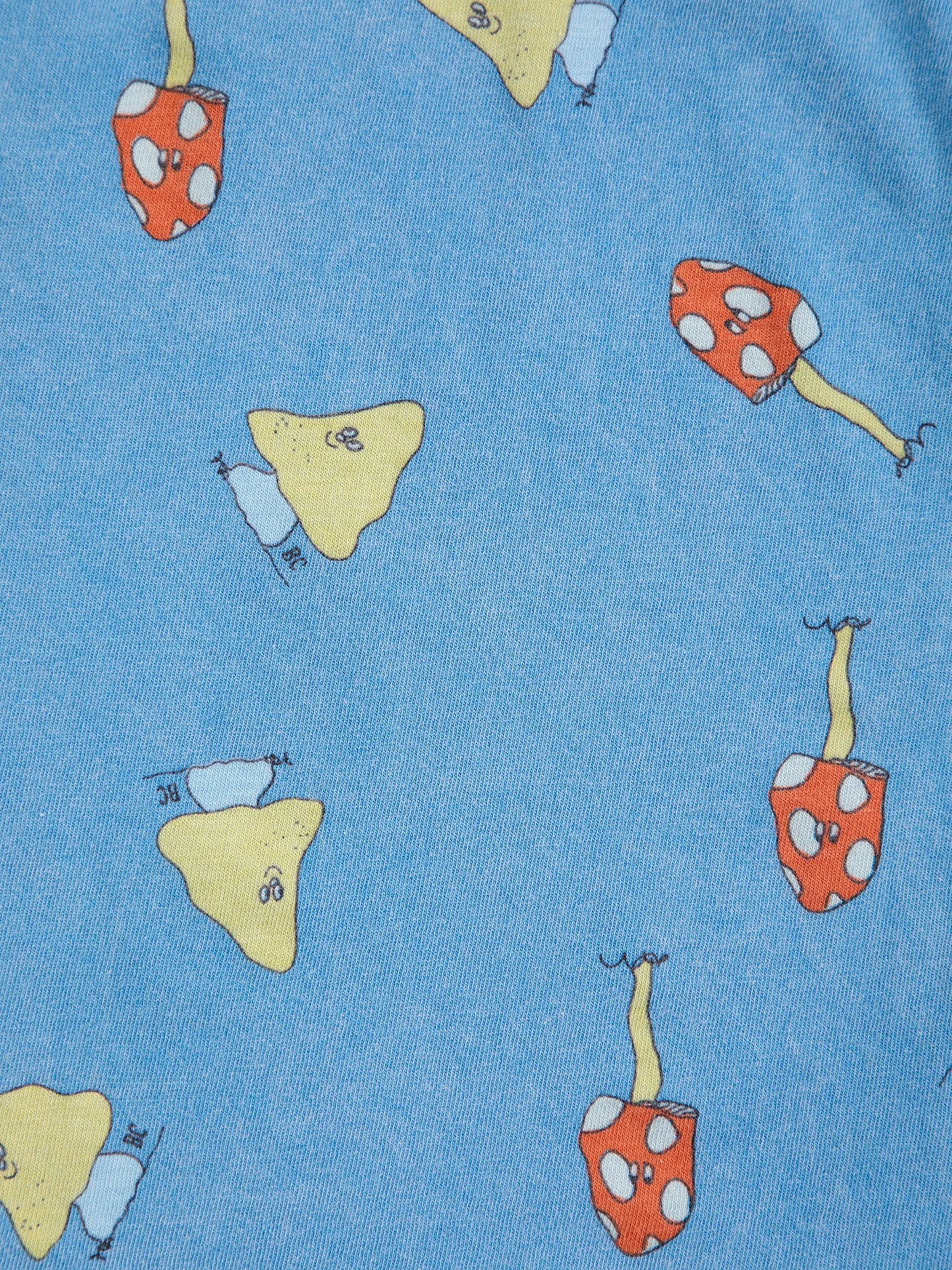 A close-up of a blue fabric surface printed with whimsical mushroom motifs in red, yellow, and light blue.