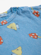 Close-up of blue fabric with cartoon mushroom patterns and a button.
