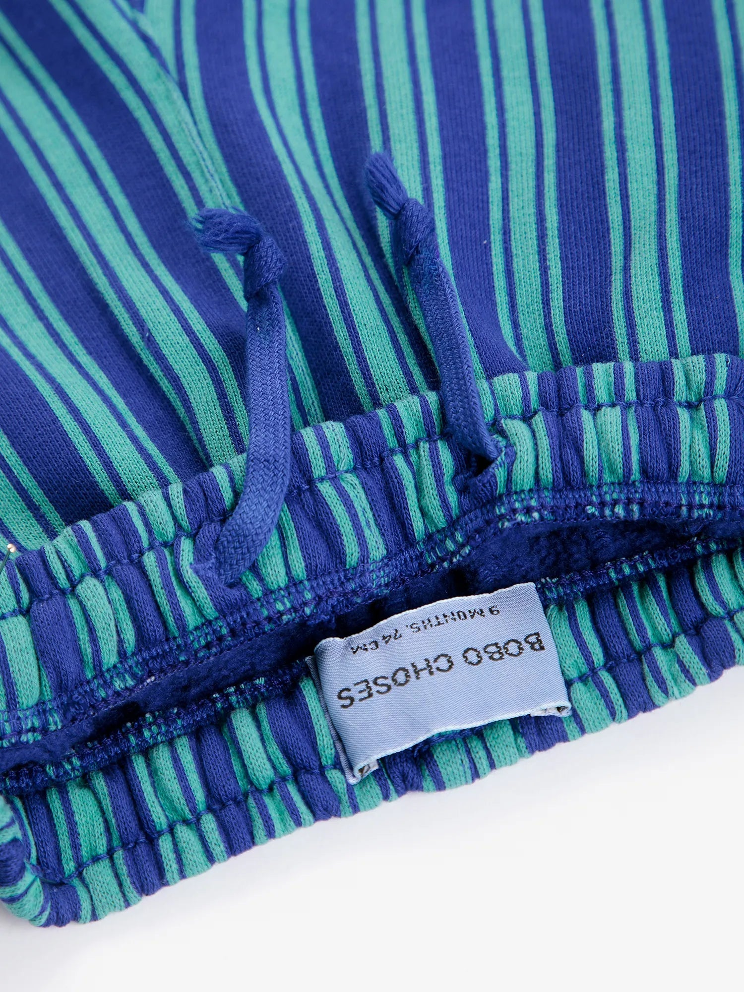 Close-up of a blue and green striped garment with a label on a white background
