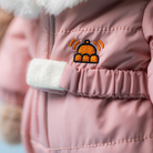 Pink children's jacket with a cartoon-like badge on the chest.
