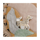 Round mat with leaf patterns, tassels, and a toy on a beige background