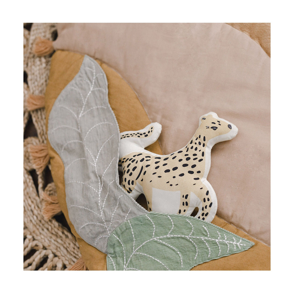 Round mat with leaf patterns, tassels, and a toy on a beige background