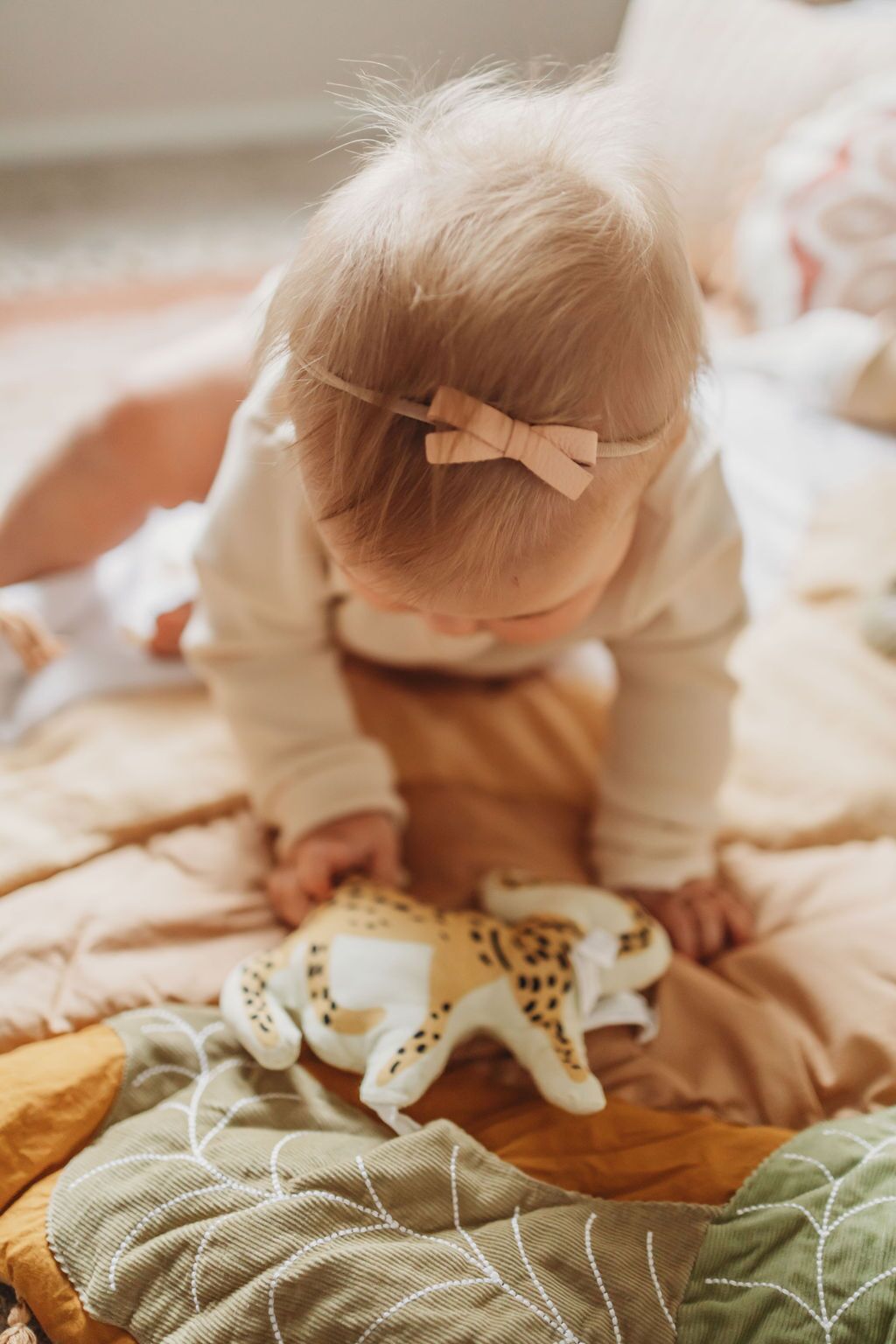 Baby sit on a children's play mat with a leaf pattern on a textured surface