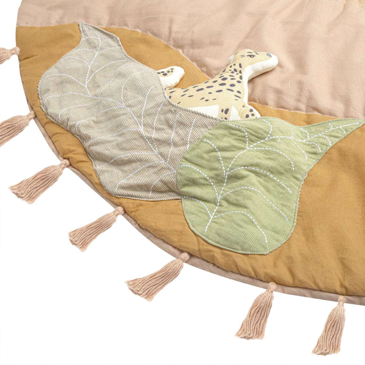 Round mat with leaf patterns, tassels, and a toy on a beige background